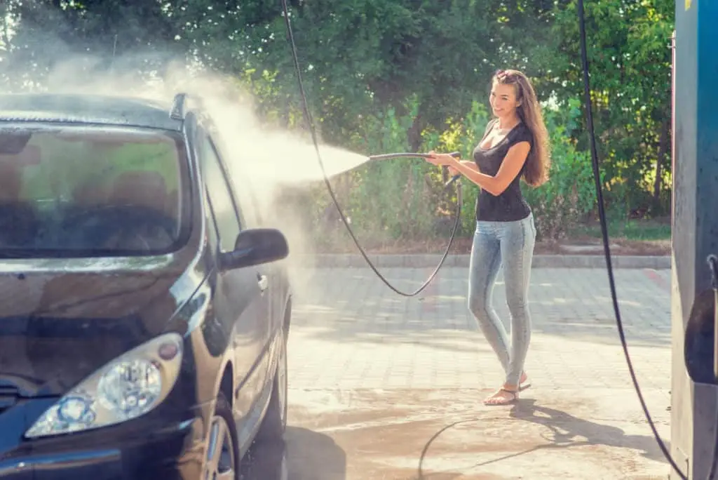 Woman washing her car with a hose